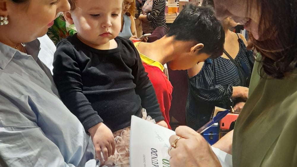 Autora Silmara Rascalha Casadei autografando exemplar do livro O Pequeno Mundo Criativo para família durante o lançamento.